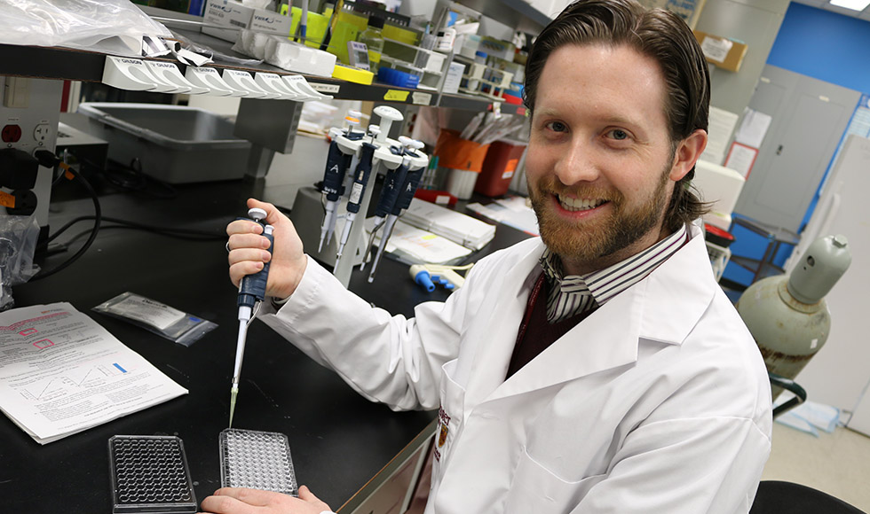 Matt Miller wearing a lab coat working in a lab.