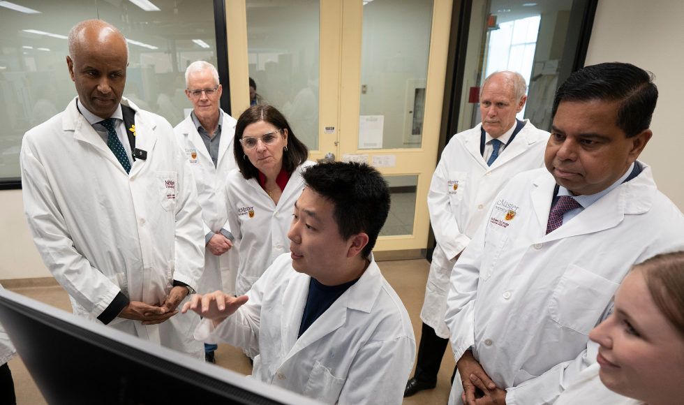 Ministers Ahmed Hussen, Filomena Tassi and Gary Anandasangaree at the Michael G. DeGroote Institute for Infectious Disease Research at McMaster, with students, Professor Eric Brown and McMaster President David Farrar.